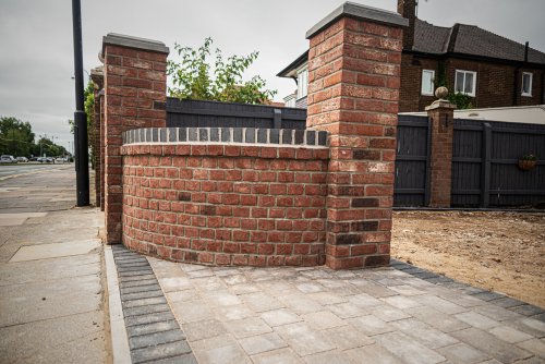 Curved red brick wall with two pillars at front of driveway